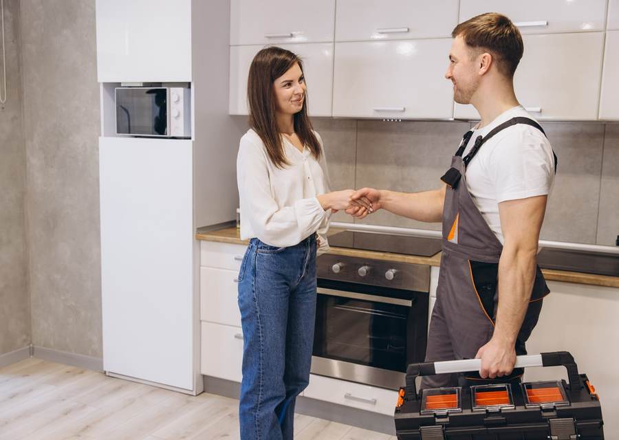 Appliance repair technician speaking with a customer in a kitchen